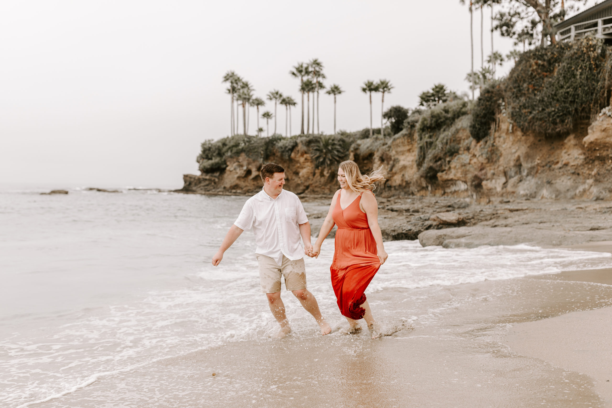 Couple holding hands and running on a beach in California