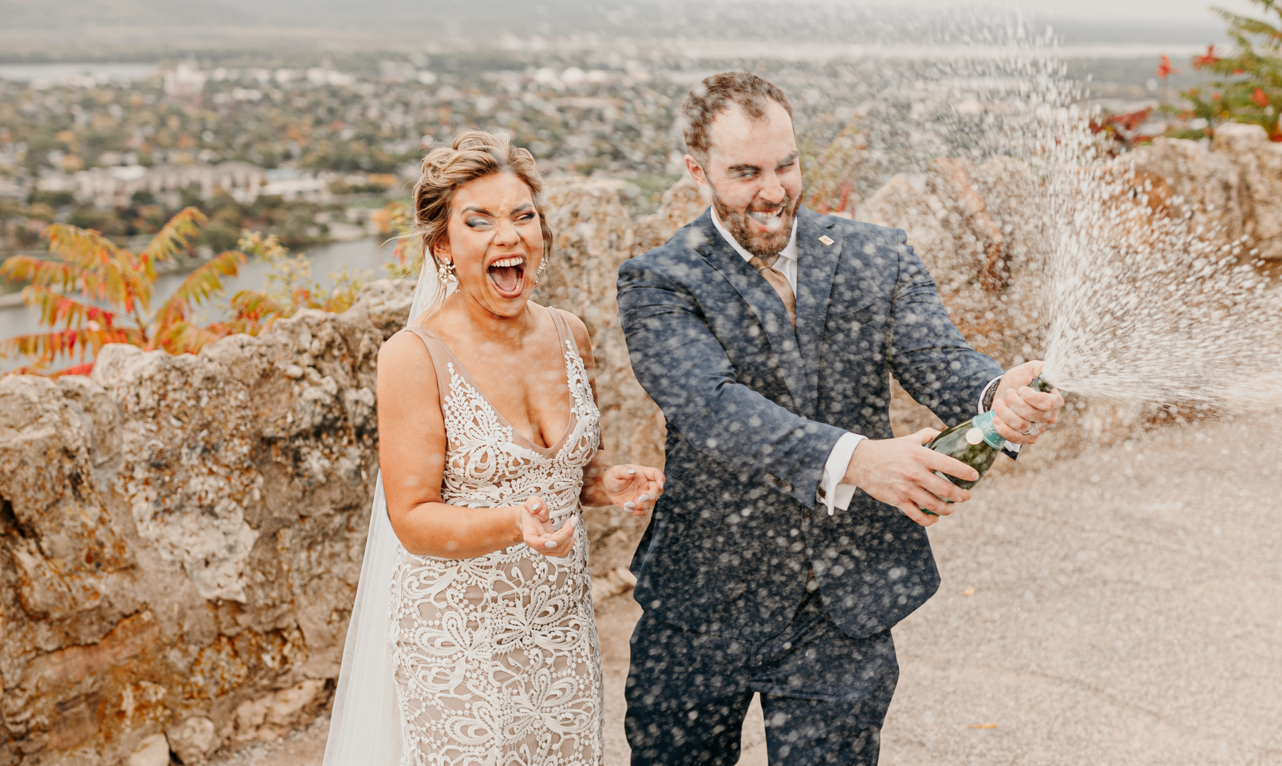 Bride and groom popping champagne on their wedding day