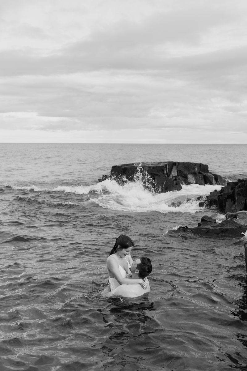 a couple holding each other in the water and laughing with one another 