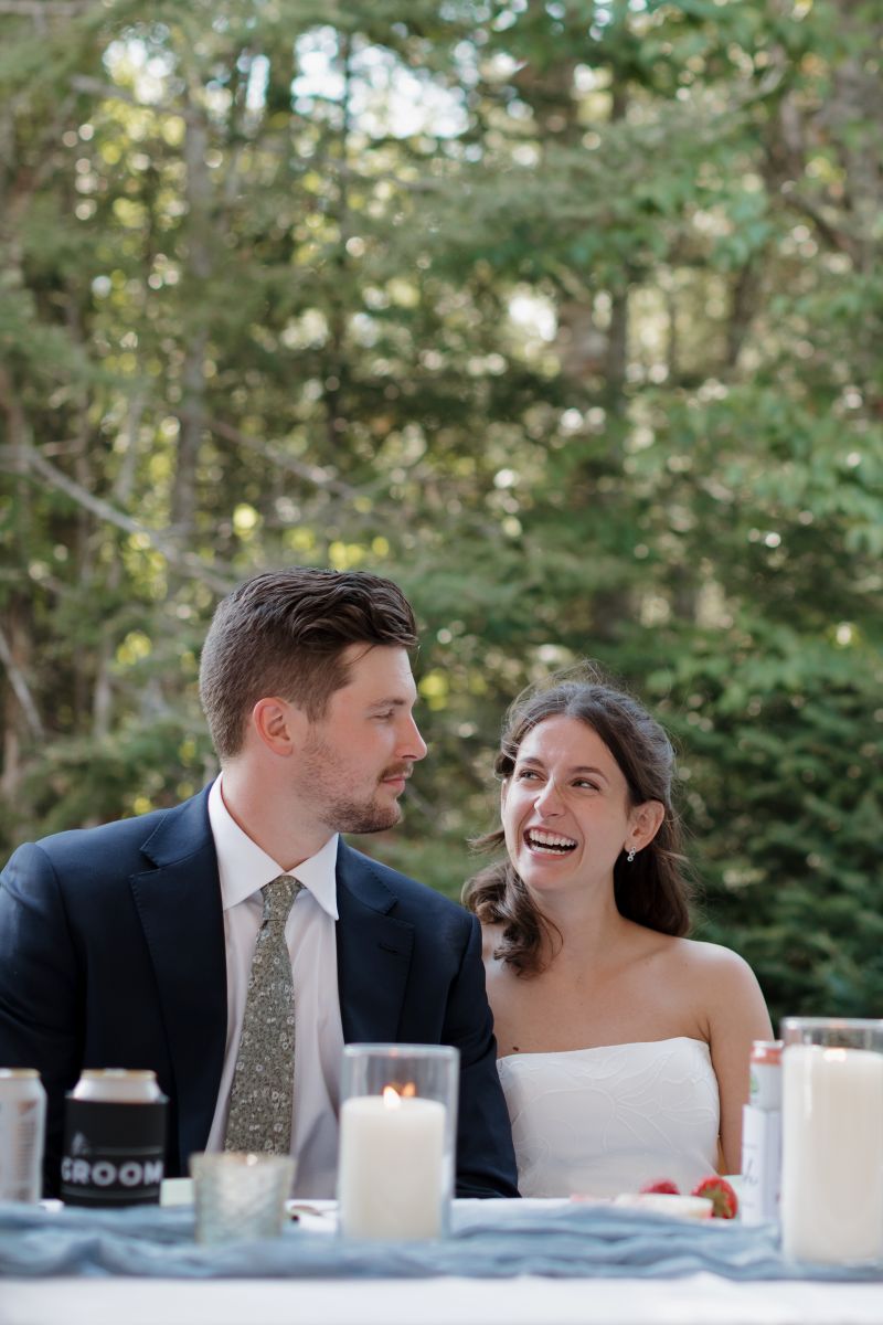 a couple laughing with one another at their wedding reception 