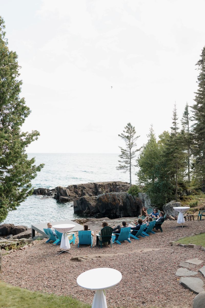 a group of guests at a wedding reception sitting in chairs next to the water