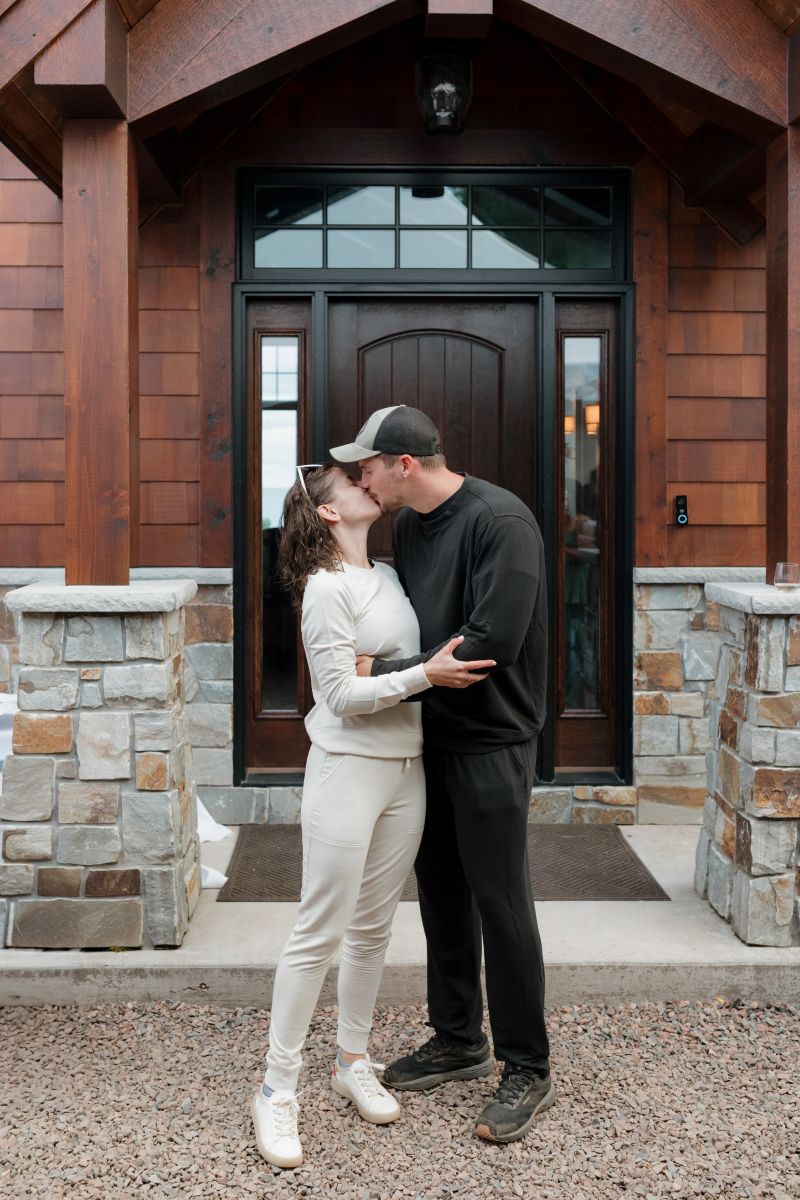 a couple kissing each other in front of a cabin 