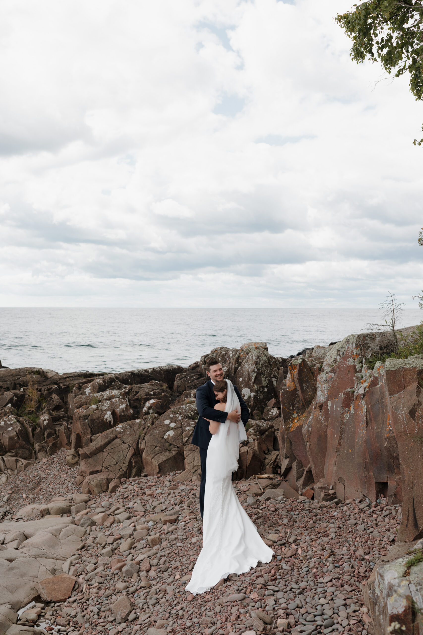 a couple taking wedding portraits next to the water in Grand Marais, Minnesota