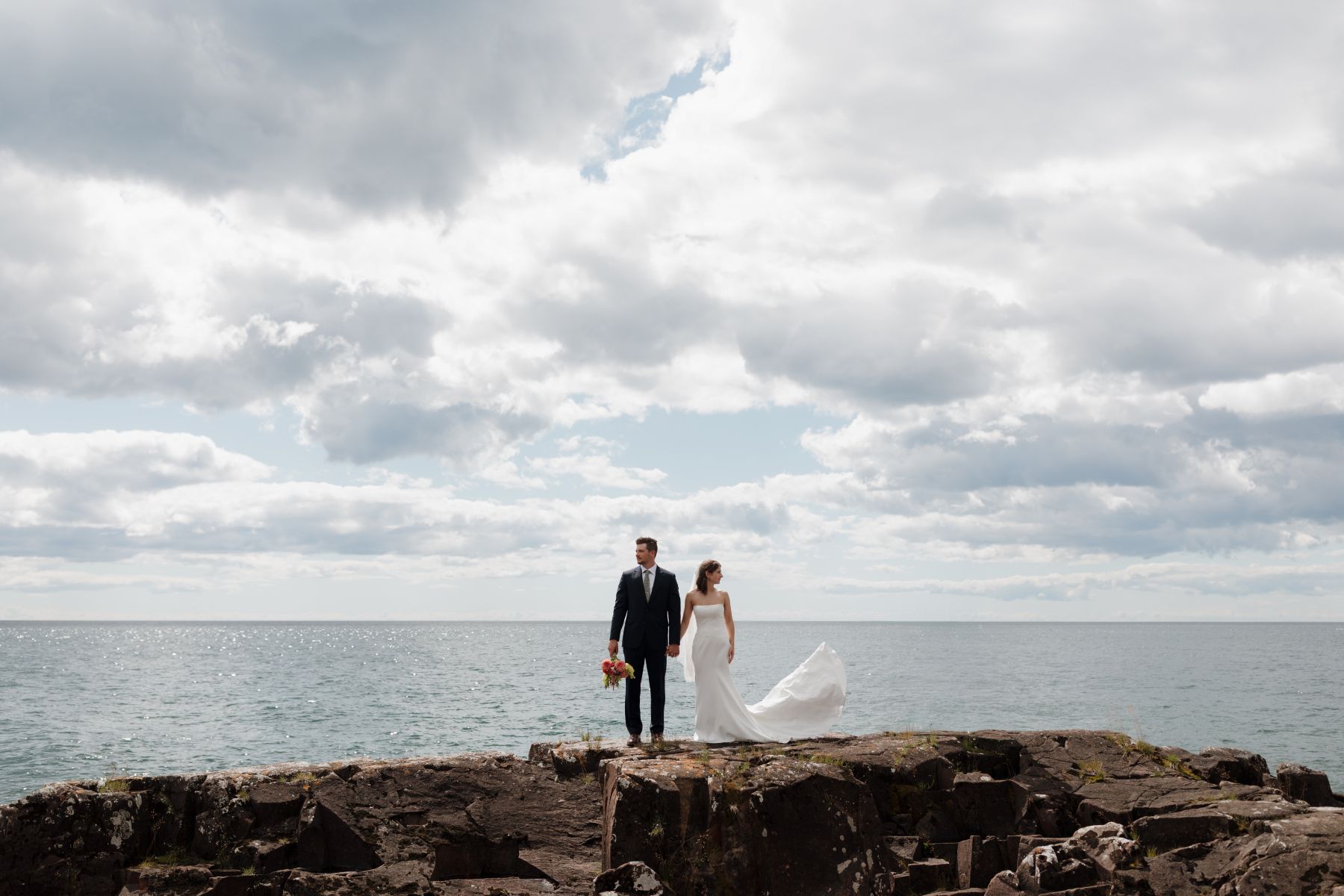 a couple taking wedding photos next to the water in Grand Marais, Minnesota 