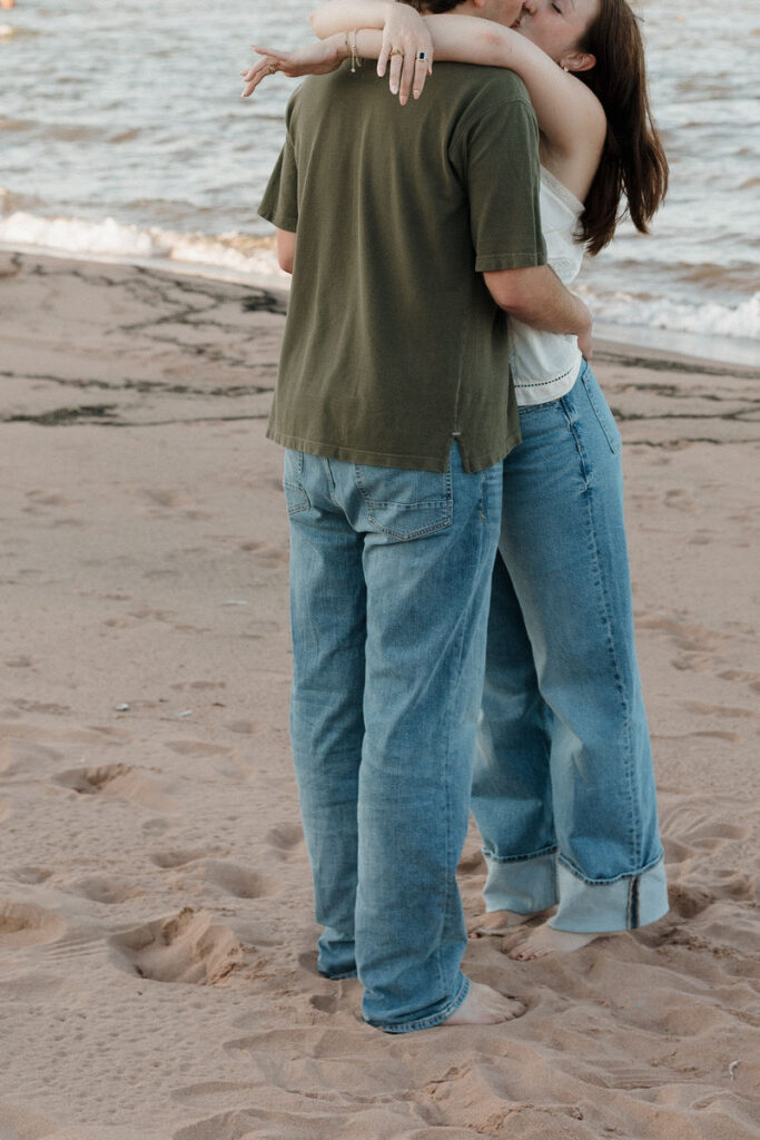 A couple hugging as they kiss on the beach 