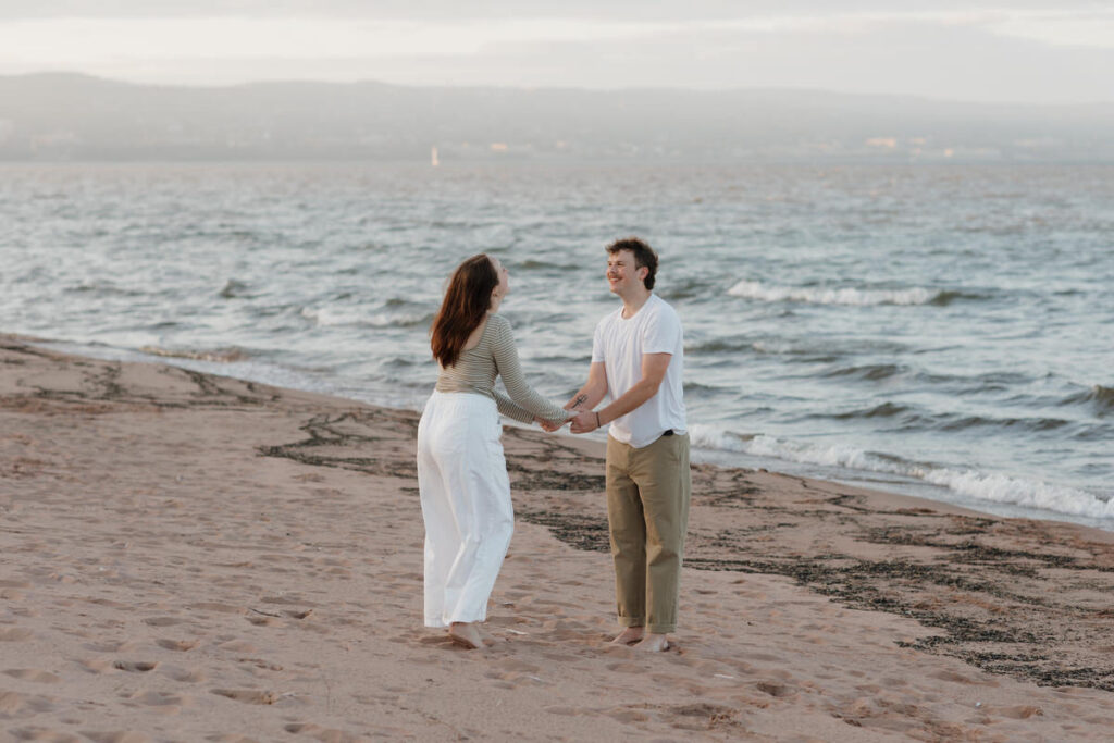 A couple holding hands and smiling while looking at each other 
