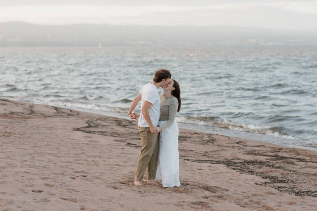 A couple holding hands and kissing on the beach 