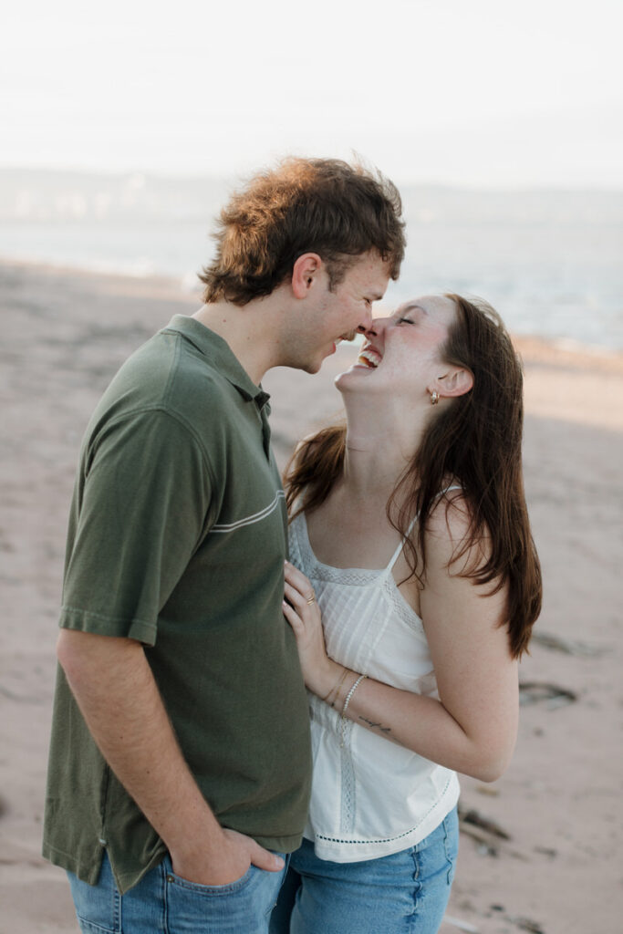 A person leaning into their partner and laughing as they are about to kiss 
