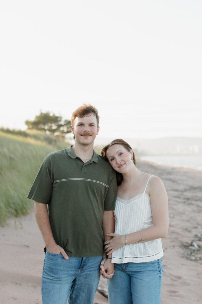A person with their arm wrapped around their partners as they lean into each other and smile 
