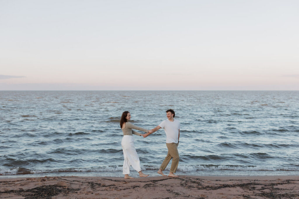 A couple holding hands and walking along the ocean's edge 