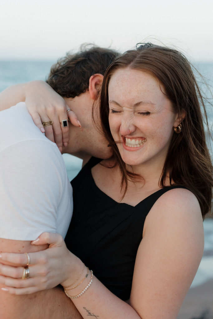 A person laughing as their partner kisses their neck 