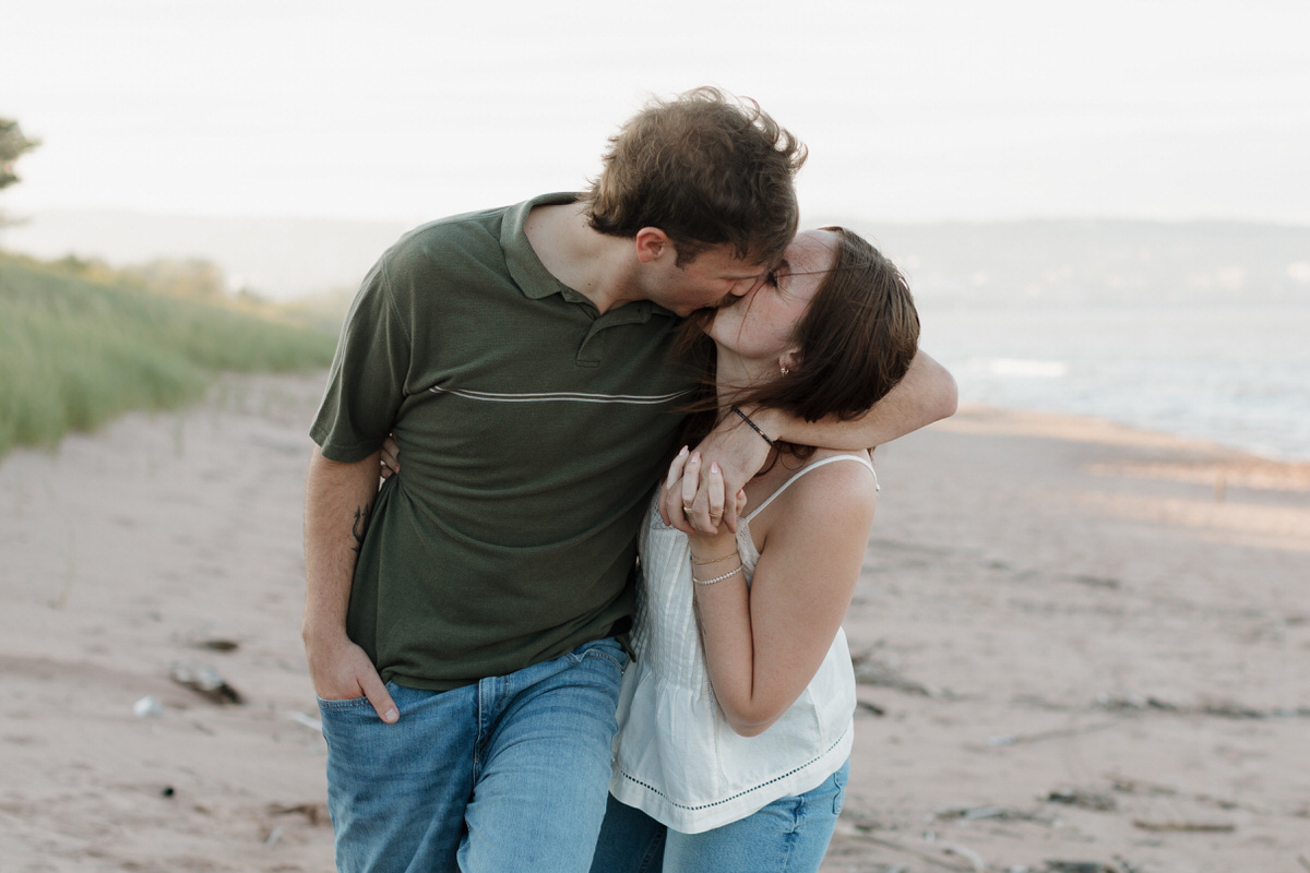 A couple running hand in hand while on the beach at Park Point, MN during their couples session with Morgan Elizabeth Photography