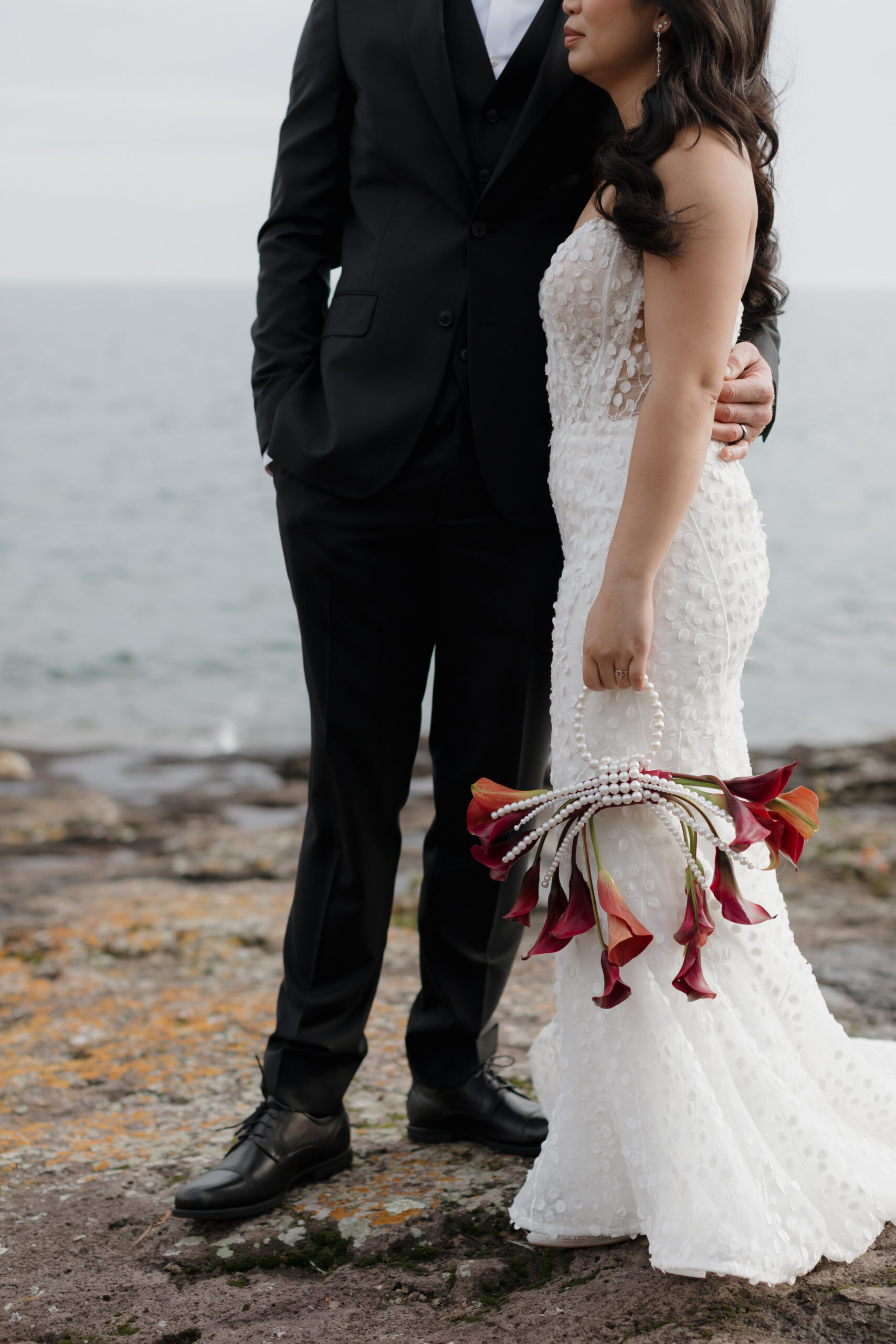 a couple taking elegant wedding portraits next to lake superior 