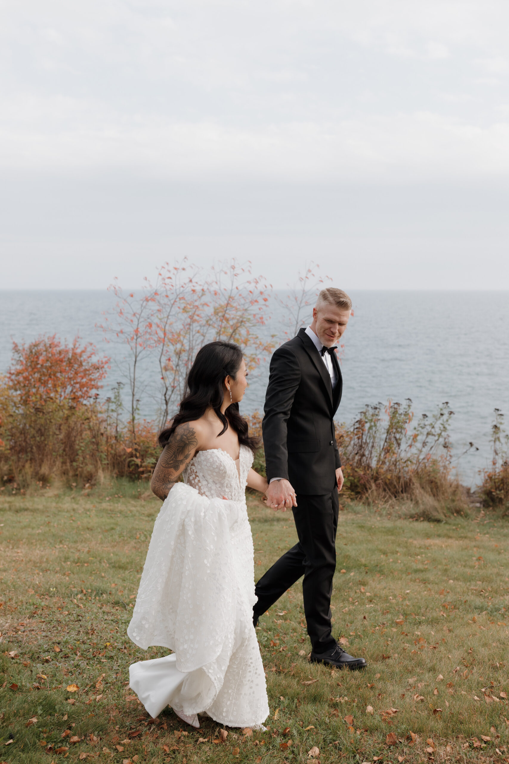 a couple walking on a grassy hillside together holding hands at bluefin bay in tofte mn 