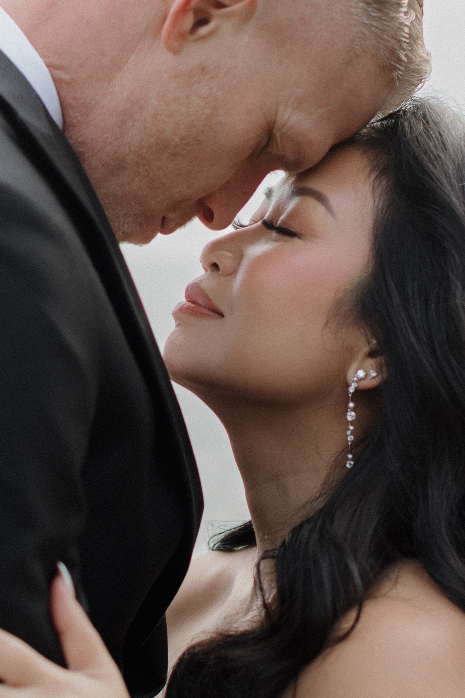 a couple taking wedding portraits together they both have their eyes closed and heads pressed together 