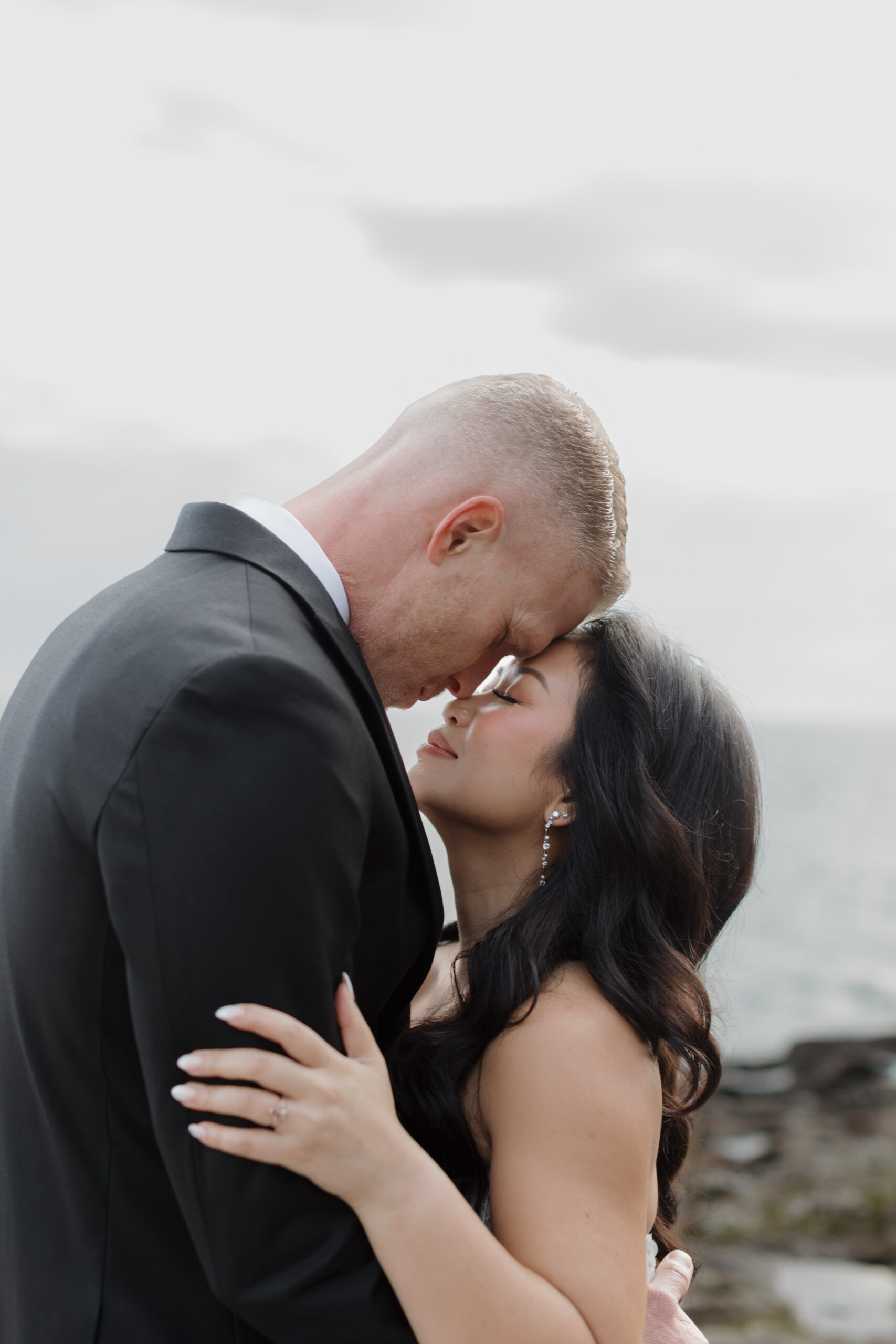 a couple pressing their heads together and embracing and standing next to lake superior 