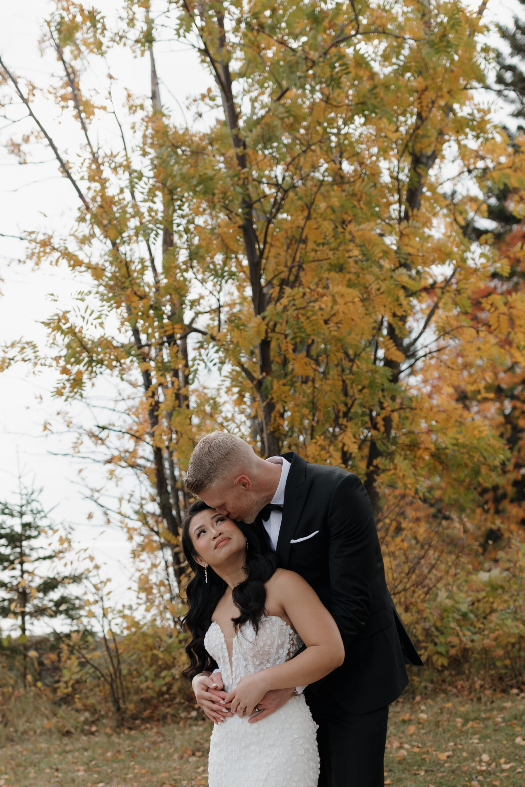 a bride and groom taking wedding portraits next to fall foliage at bluefin bay in tofte mn